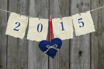 Year 2015 on antique paper and heart hanging from clothesline