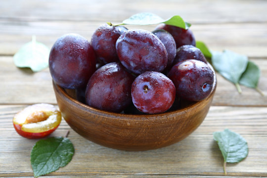 fresh juicy plums in brown bowl