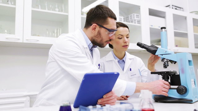 scientists with tablet pc and microscope in lab