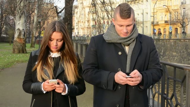 couple walk in city and work on smartphone