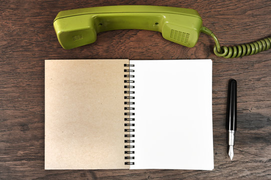 Vintage rotary telephone and pen with notebook.