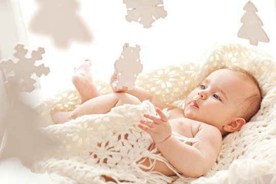 Cute little girl play with wood snowflakes in her cozy white bed