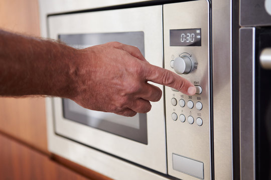 Close Up Of Hand Setting Timer On Microwave Oven