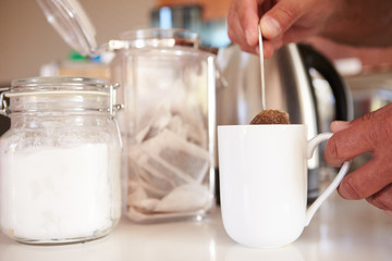 Close Up Of Man Making Tea In Cup Using Teabag