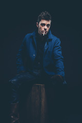 Winter jeans fashion man with short dark hair smoking a cigarett