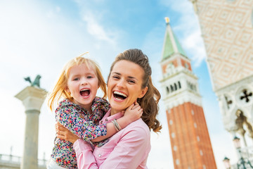 Portrait of happy mother and baby against campanile di san marco - obrazy, fototapety, plakaty