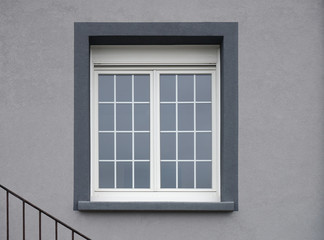 Modernes PVC Fenster mit Fensterkreuzen in grauer Fassade