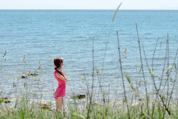 Fototapeta na wymiar Attractive young woman in shorts and blouse on background of sea