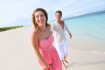 Cheerful couple running on a sandy beach