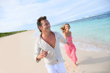 Couple having fun running on a caribbean beach