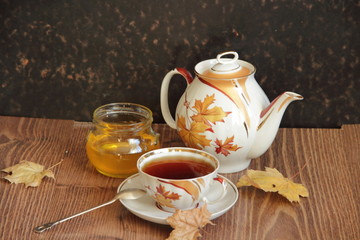 Fototapeta na wymiar Still-life with a cup of tea, honey and autumn leaves