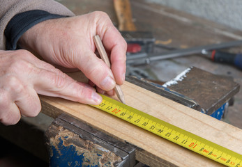 a worker measuring a board with a tape measure