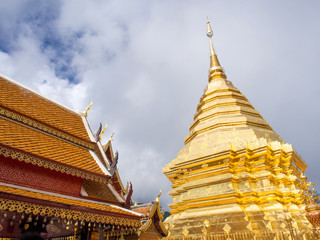 Fototapeta premium Golden pagoda of Wat Phra That Doi Suthep under cloudy blue sky
