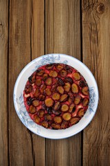 Upside down plum pie on wooden background