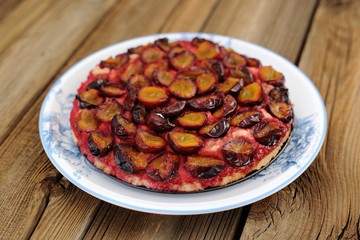Upside down plum cake on wooden background