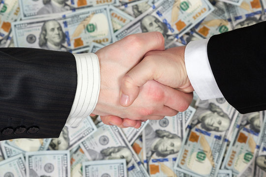 Handshake of businessmen on banknotes background