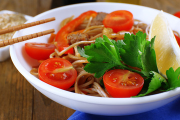 Chinese noodles with vegetables and roasted meat in bowl