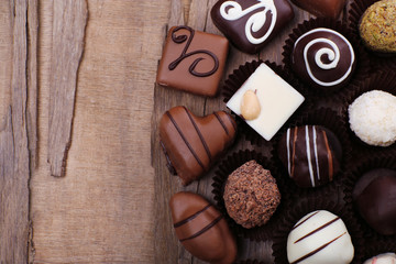 Many chocolates on wooden textured background