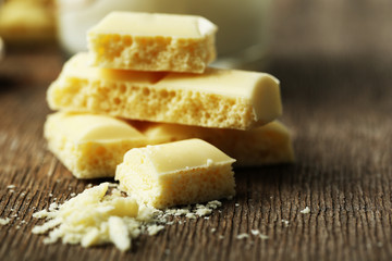 Tasty white porous chocolate on wooden table, close up