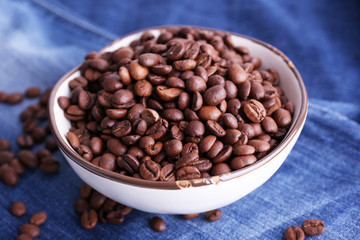 bowl of coffee beans stands on jeans background