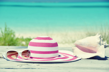 Fototapeta na wymiar Sun glasses and hat against tropical beach of Great Exuma island