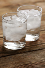 Glasses with ice cubes on wooden table