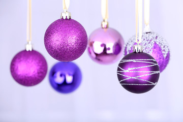 Obraz premium Hanging purple Christmas toys on light background