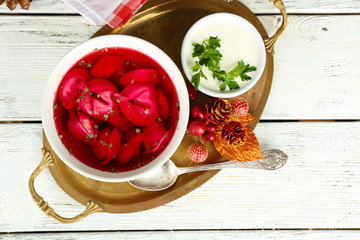 Traditional polish clear red borscht with dumplings in bowl