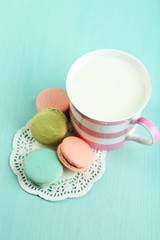 Assortment of gentle colorful macaroons and mug with milk