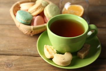 Colorful macaroons with cup of tea on wooden background