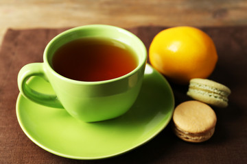 Cup of tea with colorful macarons on wooden background