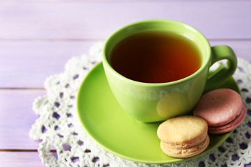 Cup of tea with colorful macarons on wooden background