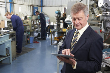 Owner Of Engineering Factory Using Digital Tablet With Staff In