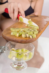 Obraz premium Portrait of pregnant mother cuts kiwi fruit