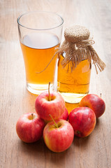 Glasses of apple juice with apples on the background.