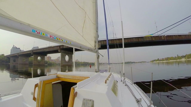 Yacht sailing under river city bridge, cityscape, pollution, POV