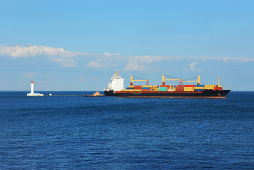 Tugboat assisting container cargo ship to harbor quayside