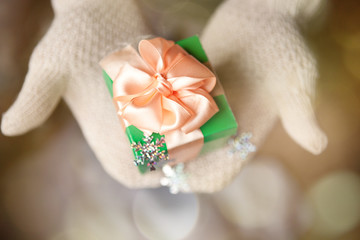 gift in hands with mittens on winter magic background