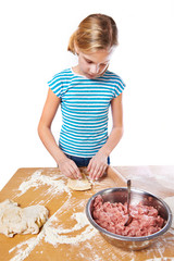Girl kneads dough for pie on kitchen table isolated