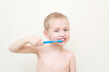 Little boy brushing his teeth blue brush in the bath