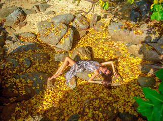 Beautyful young girl posing on boulders among leaves