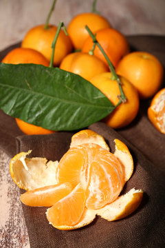 Juicy ripe tangerines with leaves on wooden table