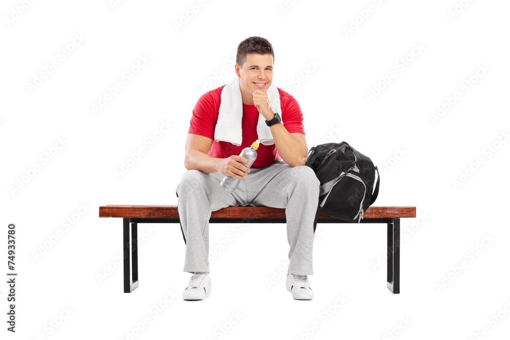 Wall mural Handsome sportsman sitting on a wooden bench