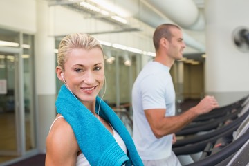 Fit young couple running on treadmills at gym