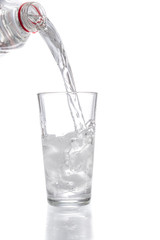 Trinkwasser aus einer Flasche in ein Glas mit Eiswürfeln gießen