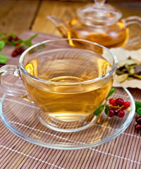 Tea with lingonberry in glass cup on bamboo napkin