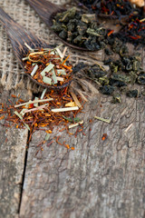 assortment of dry tea in spoons on wooden surface