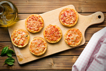 mini pizza on cutting board - obrazy, fototapety, plakaty