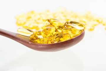 Omega 3 fish oil capsules on wooden spoon