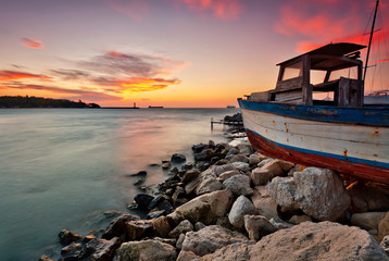 Sunset view with an old boat at the Black sea coast